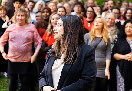 En person står framför en folkmassa och talar eller engagerar sig.